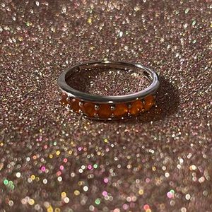 Sterling silver ring with orange stones on the front half.